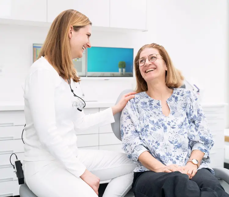 Zahn&auml;rztin sitzt neben einer Patientin und bespricht den Behandlungsplan